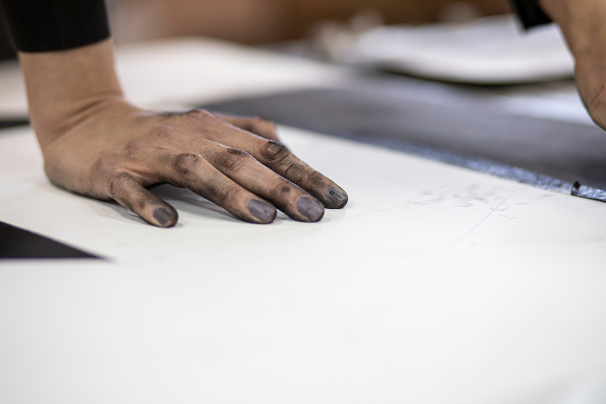 Hands of a young artist working on charcoal drawing