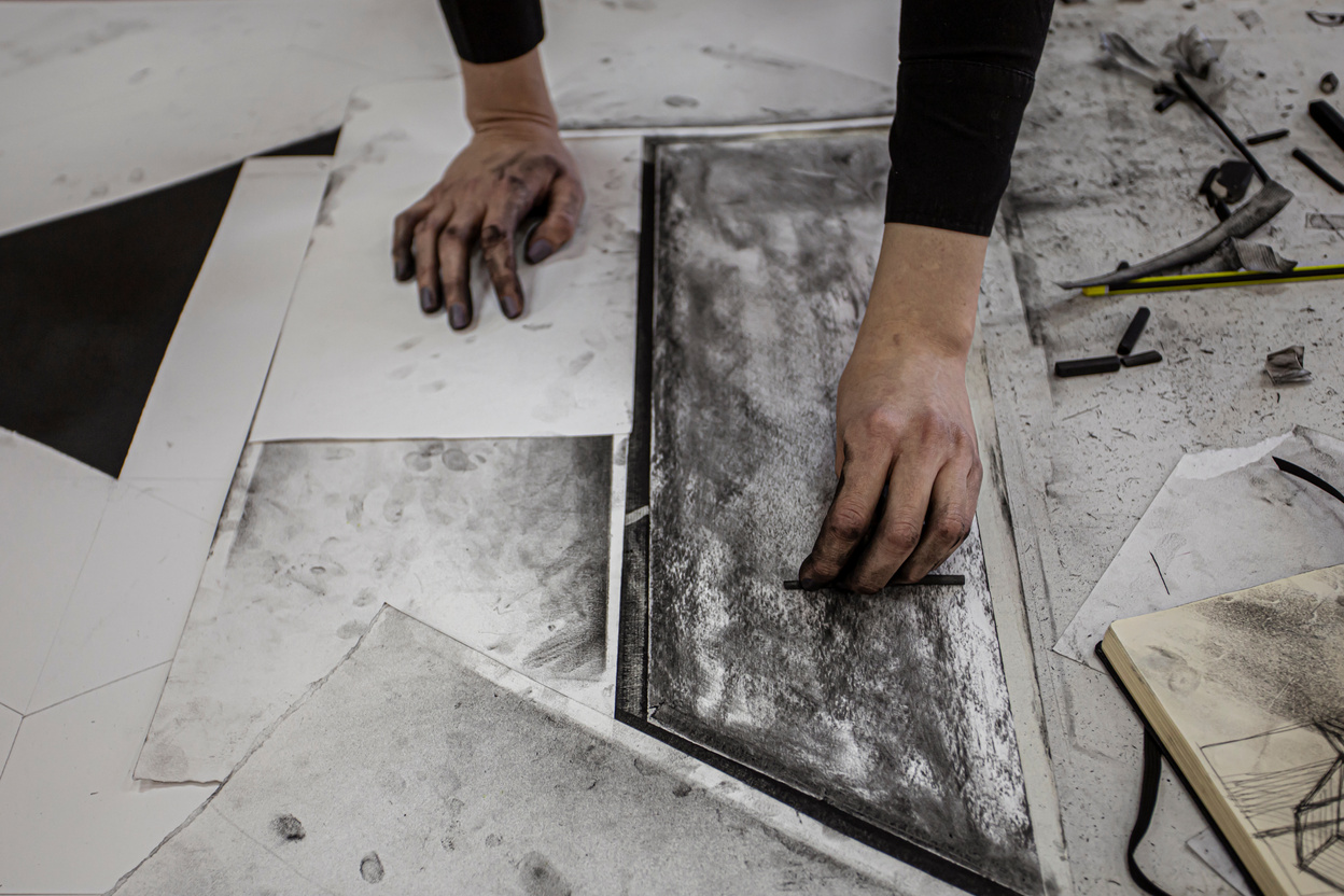 Hands of a young artist working on charcoal drawing